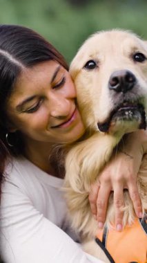 Gülümseyen bir kadının, sevgili Golden Retriever 'ını nazikçe kucakladığı güzel bir an. Bir evcil hayvanla sahibi arasındaki güçlü bağ barizdir.