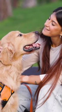 Güzel Golden Retriever köpeğinden sevgi dolu öpücükler alan mutlu genç bir kadın. Sevimli köpek gülümseyen sahibine sevgisini gösteriyor.