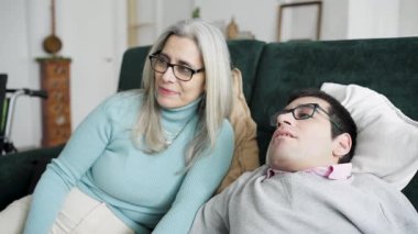 Fiziksel bir rahatsızlığı olan annesini ve oğlunu sevmek kanepede tatlı bir sohbetin tadını çıkarmak. Gülümsüyorlar, el ele tutuşuyorlar ve oturma odalarında bir an olsun bağ kuruyorlar.