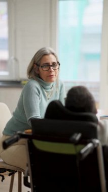 Olgun bir kadınla tekerlekli sandalyede spina bifida hastası biri arasında geçen samimi bir konuşma. İki kişi kapalı bir ortamda konuşuyor. Dikey