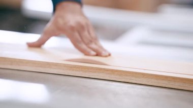 Profesyonel katılımcı dairesel bir testereyle ahşap bir tahta kesiyor. Bir ahşap atölyesinde elin ve bıçağın yakın çekimi.