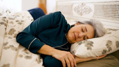 Son sınıf öğrencisi kadın rahat bir şekilde yatakta dinleniyor, pijama giyiyor, huzurlu bir gece geçiriyor, rahat bir yatak odasında uyuyor.
