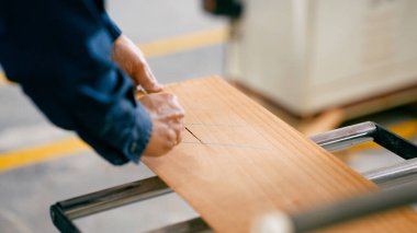 Bir zanaatkârın elleri ahşap tahtayı keserken el testeresi kullanır, profesyonel bir atölyede ahşap işçiliği yapar.