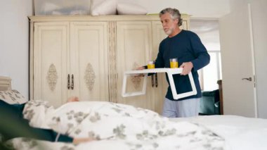 Bakıcı yaşlı koca karısına yatakta portakal suyu ile kahvaltı tepsisi getiriyor. Romantik sabah sürprizi ve aşk işareti