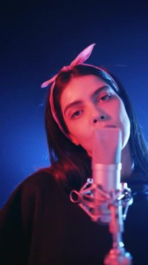 Kadın şarkıcı tutkuyla bir stüdyoda reggaeton şarkısı söylüyor. Sanatçı profesyonel bir mikrofona şarkı söylüyor.