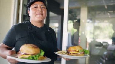 Gururlu İspanyol garson iki lezzetli hamburger tabağı ve patates kızartması servis ediyor. Müşteri siparişini teslim etmek için restoranda yürüyor.