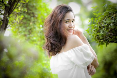 parkta kameraya bakan beyaz elbiseli güzel asyalı kadın portresi