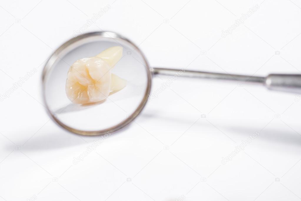 Dentist mirror with reflection of teeth in a white background