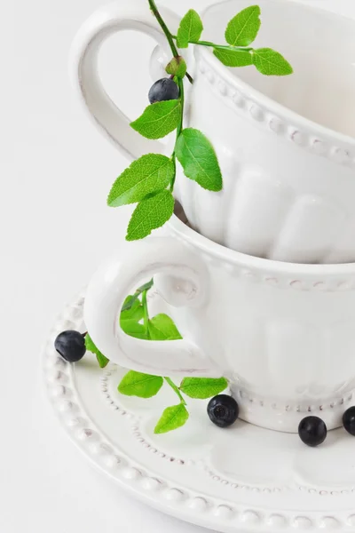 Weiße Tasse und ein Zweig mit Blaubeeren — Stockfoto