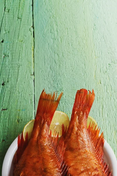 Копченый морской окунь на зеленом фоне — стоковое фото