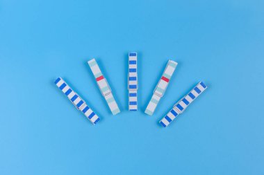 Açık mavi arkaplanda beş tahta mandal..