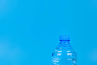 Mavi arka planda plastik bir su şişesinin tepesinde.. 