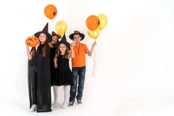 Un grupo de niños con disfraces de Halloween están parados sobre un fondo blanco y sonriendo. espacio de copia —  Fotos de Stock