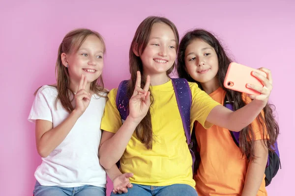 Três meninas adolescentes sorrindo e filma um vídeo em um fundo rosa. Selfies. Fotos De Bancos De Imagens