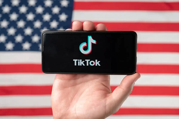 Logotipo do aplicativo Tiktok em um smartphone com fundo bandeira americana. Donald Trump banirá Tiktok nos Estados Unidos. Rússia, Kazan - 08 de agosto de 2020 Fotos De Bancos De Imagens Sem Royalties