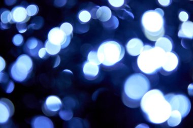 Siyah arka planda bir sürü bokeh noeli büyük mavi ve beyaz ışık var. Bulanık mavi parıltılı doku. Noel, yeni yıl ya da festival arka planı için mavi bokeh simli duvar kağıdı. 