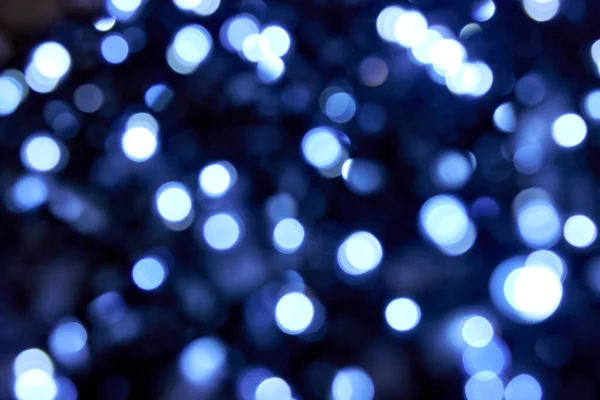 Bulanık mavi parıltılı doku. Soğuk mavi ışık. Siyah arka planda bir sürü bokeh noel beyaz ve mavi ışık var. Noel, yeni yıl ya da festival arka planı için mavi bokeh simli duvar kağıdı. 