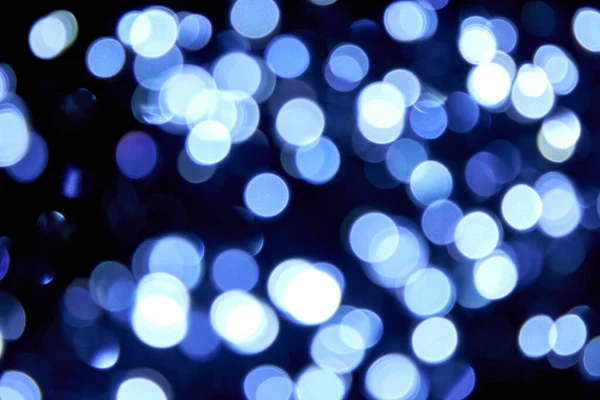 Birçok kişi siyah arka planda Bokeh noel mavi ışıklarını söndürdü. Bulanık mavi parıltılı doku. Noel, yeni yıl, festival arka planı için mavi bokeh simli duvar kağıdı.