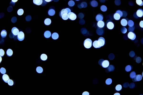 Siyah arka planda odaksız küçük mavi ışıklar. Bulanık mavi parıltılı doku. Noel, yeni yıl ya da festival arka planı için mavi bokeh simli duvar kağıdı. 