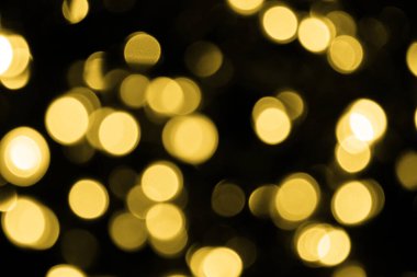 Odaklanamayan Bokeh Noel 'i siyah arka planda büyük altın ışıklar. Bulanık altın parıltısı dokusu. Noel, yeni yıl ya da festival arka planı için altın parlayan duvar kağıdı.