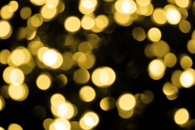 Odaklanamayan Bokeh Noel 'i siyah arka planda büyük altın ışıklar. Bulanık altın parıltısı dokusu. Yeni yıl, Noel, festival arka planı için altın parlayan duvar kağıdı.