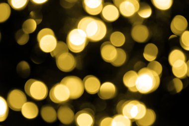 Odaklanamayan Bokeh Noel 'i siyah arka planda büyük altın ışıklar. Bulanık altın parıltısı dokusu. Noel, yeni yıl ya da festival için altın renkli duvar kağıdı, tatil arka planı.
