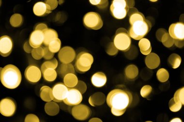 Odaklanamadığı Bokeh Noel 'i. Siyah arka planda büyük altın ışıklar. Bulanık altın parıltısı dokusu. Noel, yeni yıl ya da festival arka planı için altın parlayan duvar kağıdı.
