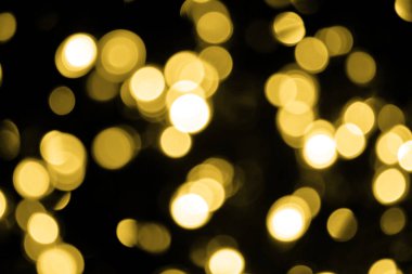 Odaklanamayan Bokeh Noel 'i siyah arka planda büyük altın ışıklar. Bulanık altın parıltısı dokusu. Noel, yeni yıl ya da festival arka planı için altın parıltılı duvar kâğıdı.