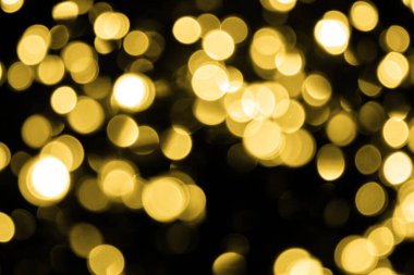 Odaklanamayan Bokeh Noel 'i siyah arka planda büyük altın ışıklar. Bulanık sarı parıltılı doku. Noel, yeni yıl ya da festival arka planı için altın parlayan duvar kağıdı.
