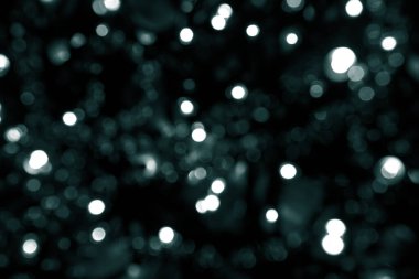 Bulanık yeşil parıltı dokusu. Tidewater yeşili renkler. Siyah arka planda bir sürü bokeh noel ışığı var. Noel, Yeni Yıl veya festival arka planı için yeşil bokeh simli duvar kağıdı. 