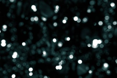 Bulanık yeşil parıltı dokusu. Tidewater yeşili renkler. Siyah arka planda bir sürü küçük bokeh noel ışığı var. Noel, Yeni Yıl veya festival arka planı için yeşil bokeh simli duvar kağıdı. 