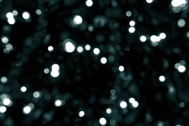 Noel, yeni yıl ya da festival geçmişi için yeşil bokeh simli duvar kağıdı. Tidewater yeşili renkler. Bulanık yeşil parıltı dokusu. Siyah arkaplanda bir sürü bokeh noeli beyaz ve yeşil ışık var.. 