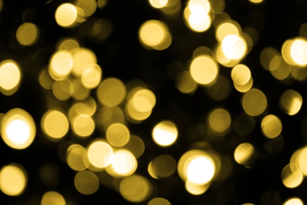 Odaklanamadığı Bokeh Noel 'i. Siyah arka planda büyük altın ışıklar. Bulanık altın parıltısı dokusu. Noel, yeni yıl ya da festival arka planı için altın parlayan duvar kağıdı.