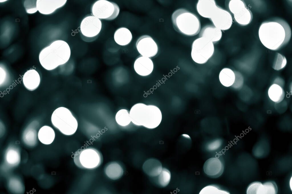 Tidewater Green colors. A lot of defocused bokeh christmas big white lights on dark background. Blurred abstract green glitter texture. Green bokeh glitter wallpaper for Christmas, New year or festival background. 