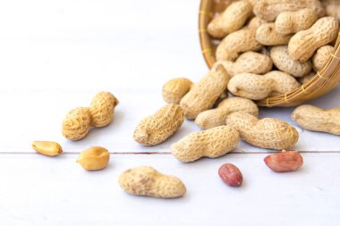 Tahta sepette yaprak ve kabukta yer fıstığı olan fıstıklar tahtadan beyaz arka planda izole edilmiş. Sağlıklı vejetaryen kavramı.