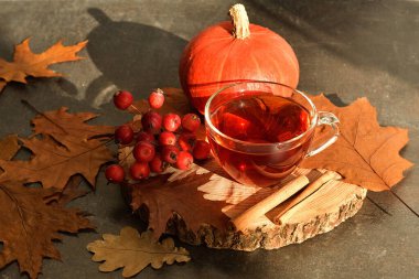 Bir fincan sıcak çay, sonbahar yaprakları ve ahşap arka planda meyveler. Kitaplar, böğürtlenler, balkabakları. Ev konforu. Sonbahar havası. Seçici odaklanma. Boşluğu kopyala