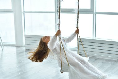 Pembe oyuncak flamingolu beyaz retro elbisesi olan tatlı, uzun saçlı kız salıncakta sallanıyor. arka plan Noel dekoru. Mutlu yıllar. Boşluğu kopyala