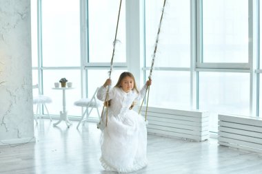 Pembe oyuncak flamingolu beyaz retro elbisesi olan tatlı, uzun saçlı kız salıncakta sallanıyor. arka plan Noel dekoru. Mutlu yıllar. Boşluğu kopyala