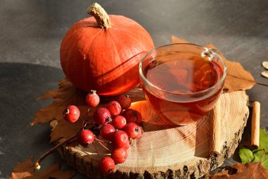 Bir fincan sıcak çay, sonbahar yaprakları ve ahşap arka planda meyveler. Kitaplar, böğürtlenler, balkabakları. Ev konforu. Sonbahar havası. Seçici odaklanma. Boşluğu kopyala