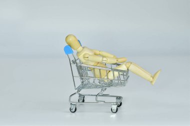 Ahşap manken alışveriş arabasında oturur. Büyük satış, zıplama konsepti. Alışverişkolik. Teslimat servisi... seçmeli odaklanma. Boşluğu kopyala