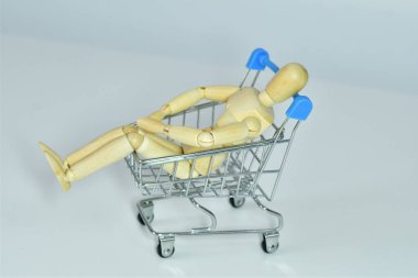 Ahşap manken alışveriş arabasında oturur. Büyük satış, zıplama konsepti. Alışverişkolik. Teslimat servisi... seçmeli odaklanma. Boşluğu kopyala