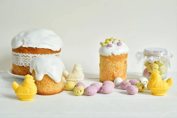 Easter sweets and decorations background. Traditional sweet cake with colorful painted eggs, chocolate hens and decor. Copy space. Selective Focus