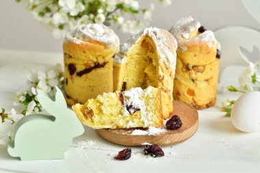 Mutlu Paskalyalar. Geleneksel Paskalya pastası, ev yapımı üzümlü Kraffin, şekerli meyveler beyaz ahşap arka planda kiraz çiçeği seçici odak. Boşluğu kopyala