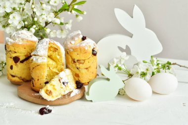 Mutlu Paskalyalar. Geleneksel Paskalya pastası, ev yapımı üzümlü Kraffin, şekerli meyveler beyaz ahşap arka planda kiraz çiçeği seçici odak. Boşluğu kopyala