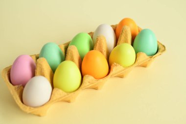 Sarı karton tepside renkli yumurtalar ve söğüt çiçeği. Paskalya dekorasyonları, kompozisyon. Renk 2021 kopyalama uzayı. Seçici odak