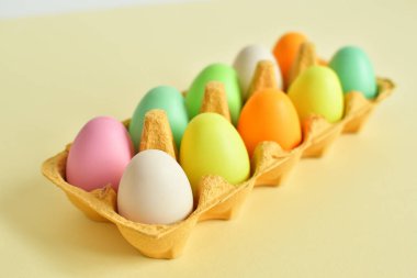 Sarı karton tepside renkli yumurtalar ve söğüt çiçeği. Paskalya dekorasyonları, kompozisyon. Renk 2021 kopyalama uzayı. Seçici odak