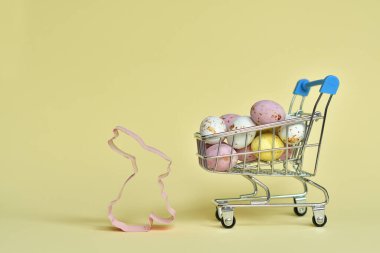 Renkli paskalya yumurtaları olan bir alışveriş arabası. Paskalya indirimi. Uzayı kopyala Seçici odak