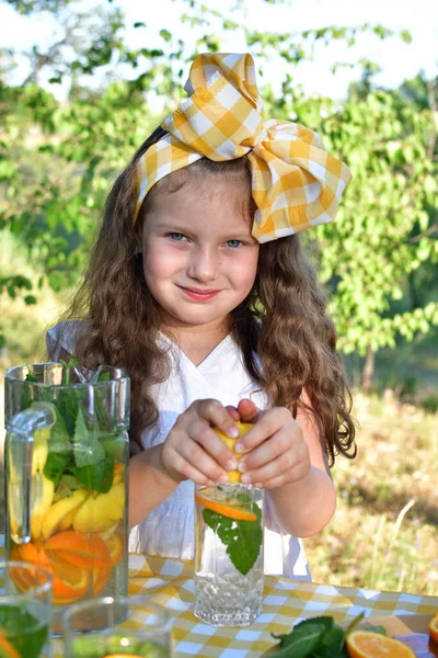 公園で彼女の顔の前にオレンジを保持している女の子 果物と子供の肖像 公園で新鮮なレモネードを準備し 楽しみを持っている女の子 — ストック写真