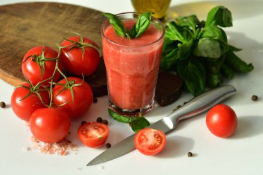 Çiğ domates ve yeşil fesleğen yapraklarıyla süslenmiş iki bardak taze organik domates suyu. Sağlıklı beslenme kavramı. Kopya alanı. Seçici odak