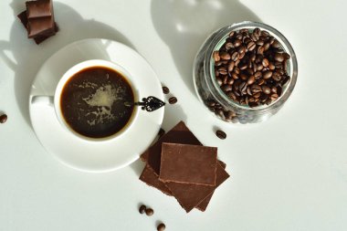 Bir fincan sade kahve ve kahve çekirdeği, bir parça çikolata. Günaydın konsept. Uzayı kopyala Seçici odaklanma. Üst görünüm